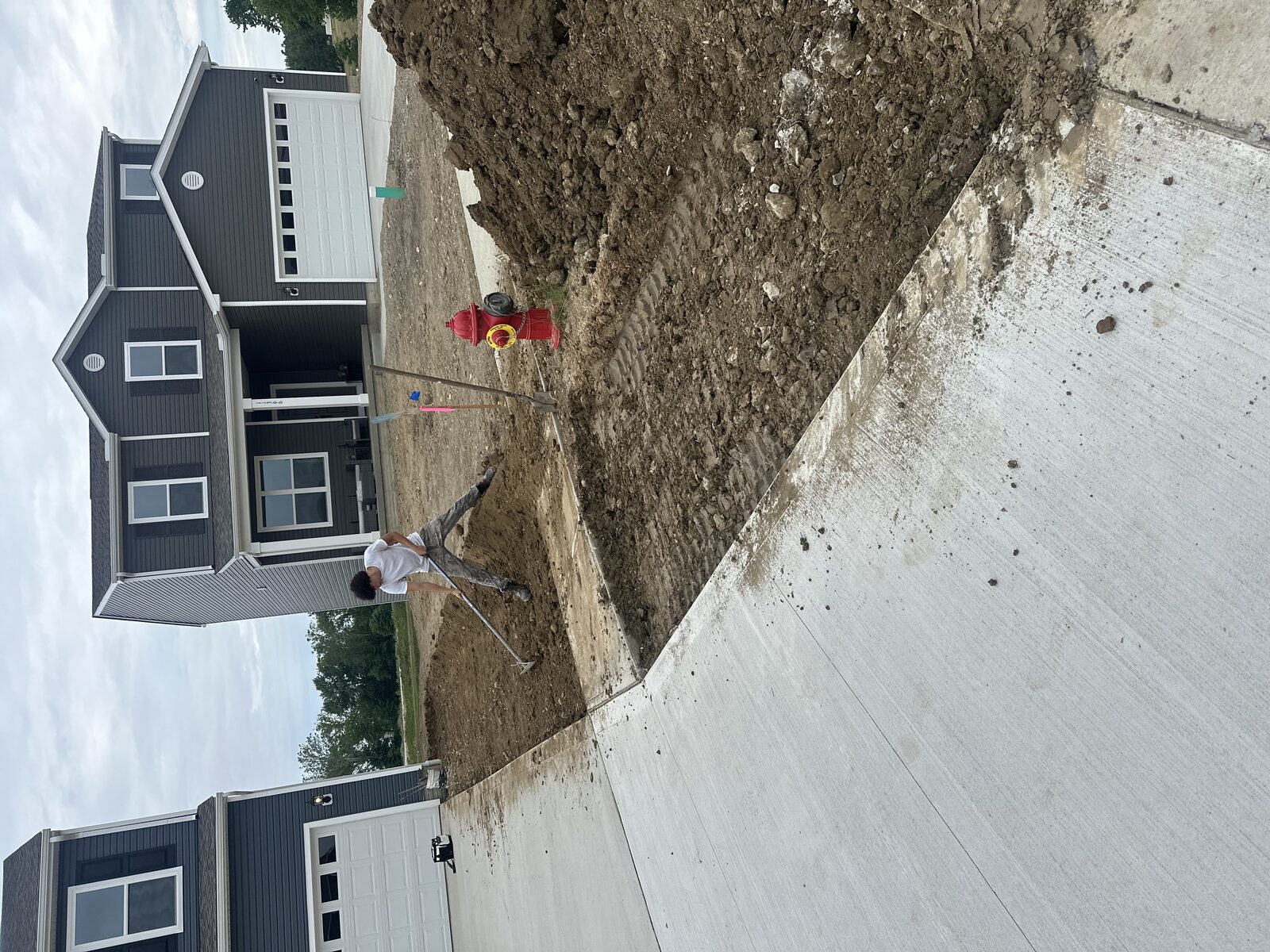 Soil being graded and cleared beside a new concrete driveway
